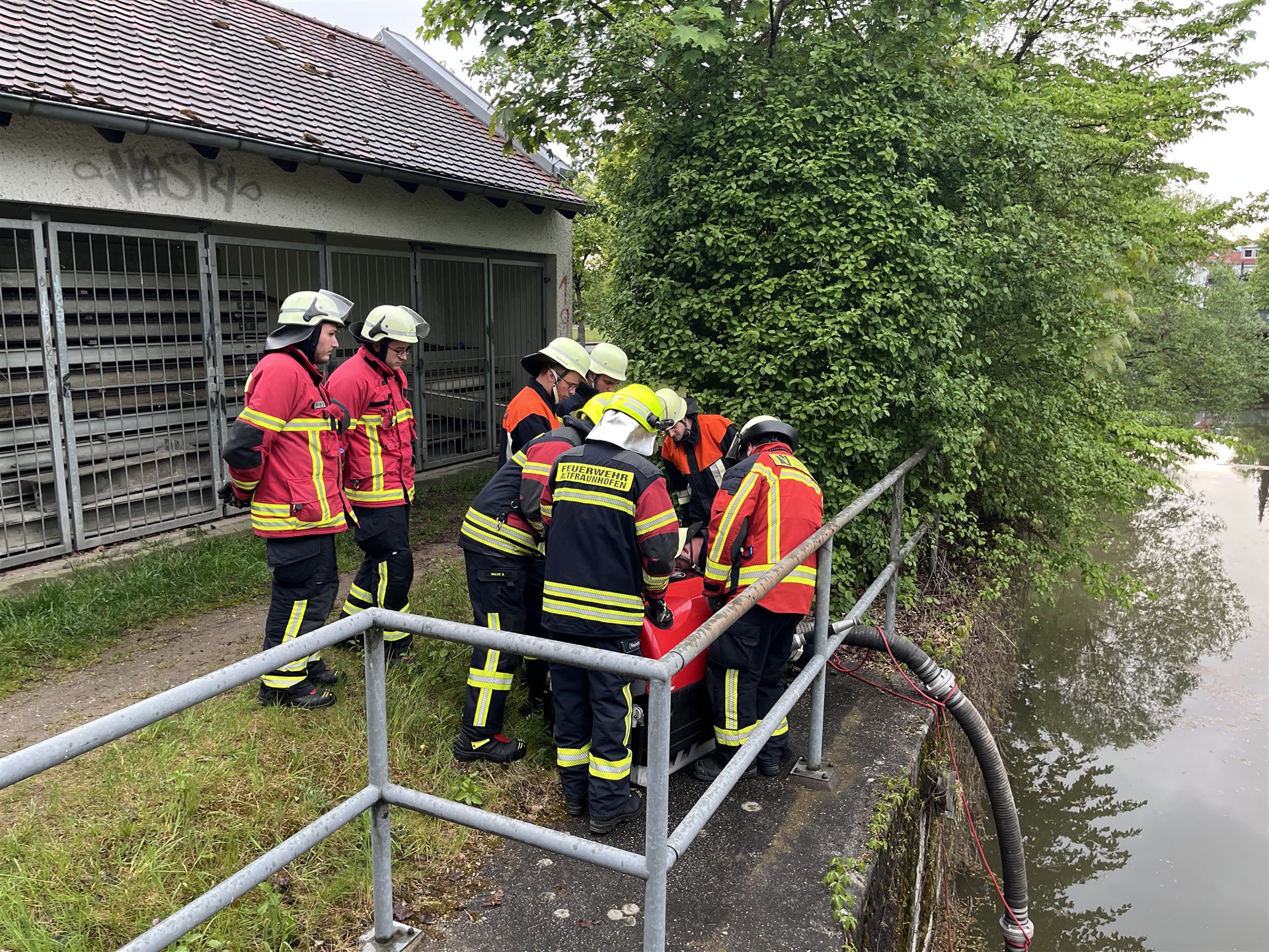 Teilnehmer in Einsatzkleidung bei der Wasserentnahme mit Saugschlauch an einem Bach